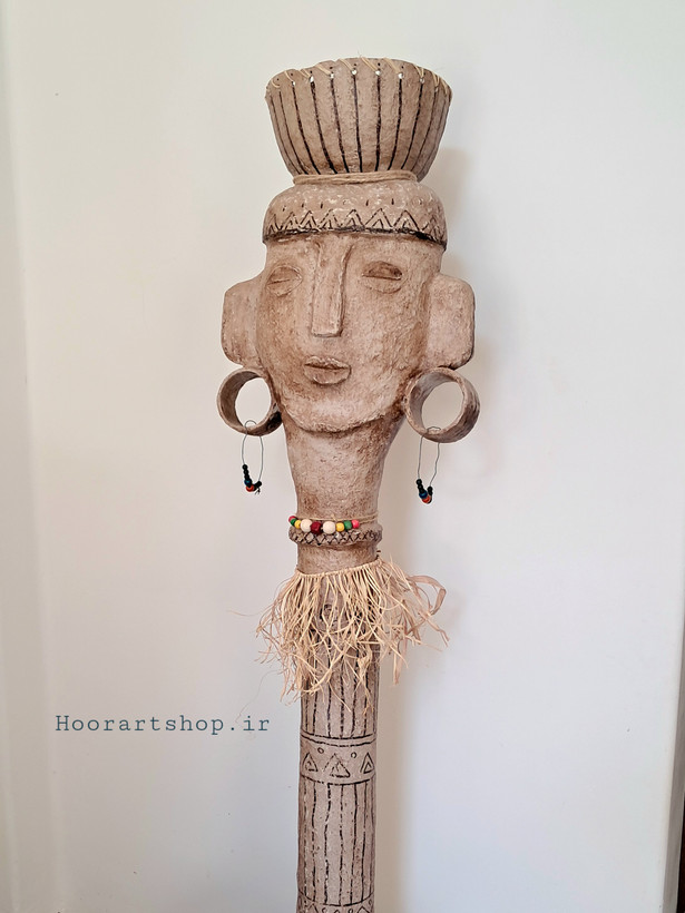 مجسمه ایستاده پاپیه ماشه بانوی آیین با طراحی الهامگرفته از هنر اقوام، بافت طبیعی، نقوش هندسی، گوشوارههای بزرگ و تزئینات الیاف طبیعی، مناسب دکوراسیون مدرن و هنری.